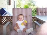 Mary sitting in a lawn chair, laid back holding a sippy-cup.