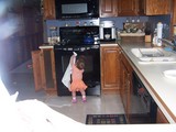 Mary holding a towel to the front of the stove as if cleaning it.