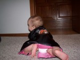 Mary crawling away from the camera.  She is wearing a silk robe that is black with pink trim.  You can see an embroidered dragon on the back and you can also see her diaper peeking out from under the robe.