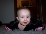 Mary on the floor in a crawling posture.  She is crawling towards the camera.  She is wearing a silk robe that is black with pink trim.
