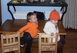 Mary and Kate at the kids table.  Kate is wearing a pumpkin hat.