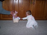 Mary crawling and reaching out to her easter bunny easter basket while mommy is holding it just out of her reach.