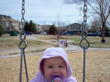 Mary sitting in the swing with her hood on and a big smile on her face.