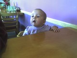 Mary sitting in a highchair.  Her tongue is pushing out on her lower lip and her head is tilted back in a haughty manner.