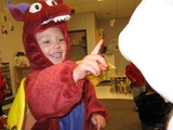 A little boy in a dragon costume pointing at Mary in her Carebear costume.