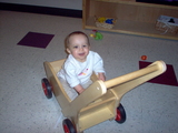 Mary sitting in the wooden cart smiling at the camera.