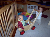 Mary pushing the wooden cart with a little boy sitting in it.