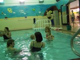 Mommy holding Miss Mary in the pool and Mary is reaching out to the baby to her left.