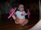 Mary sitting on the floor holding mommy's flip-flops trying to put them on her feet.