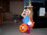 Mary in her floppy hat with a plastic jack-o-lantern on each arm and her baby doll.