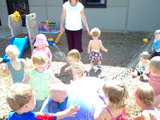 Mary and all the kids in her class running around a giant ball that squirts water out at them.