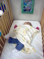 Mary asleep in her crib.  Her leg is tilted out to the side at an unnatural angle.